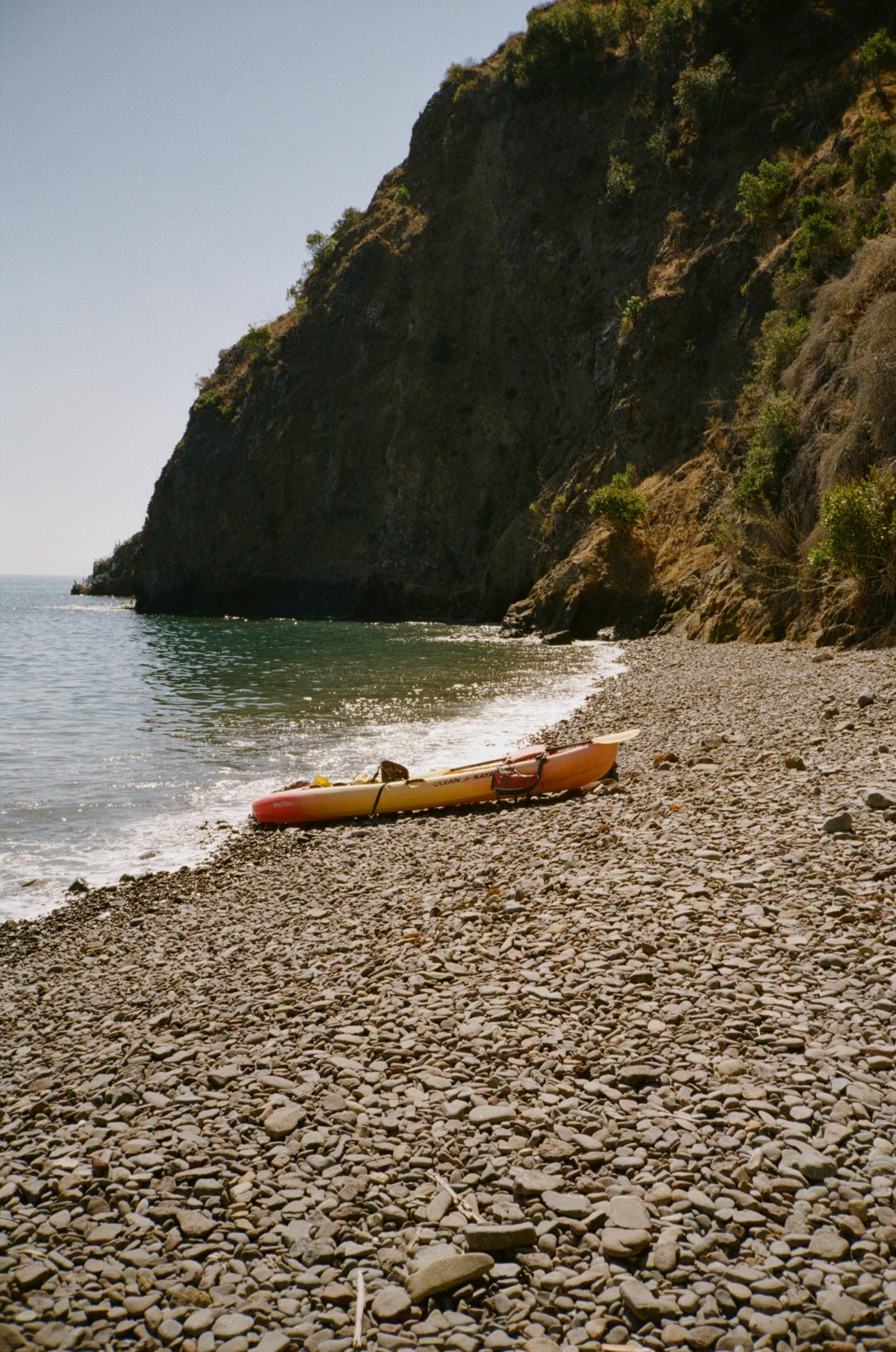 Kayak on a pebble beach below cliffs