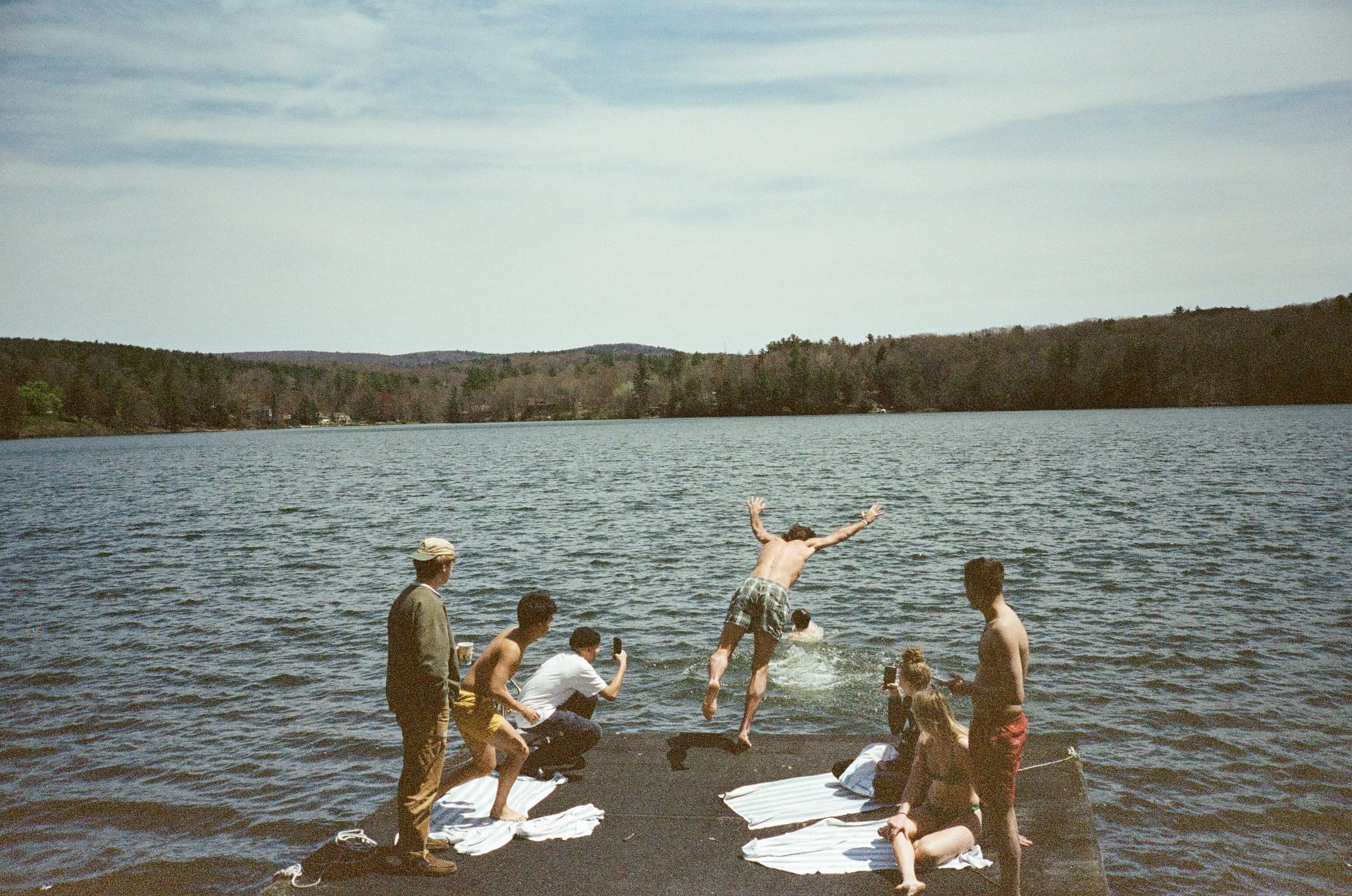 Friends jumping off a dock into a lake